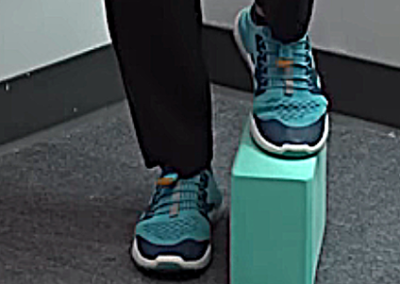 Image of Tara Tobias stepping on a yoga block flipped horizontally with her left foot.